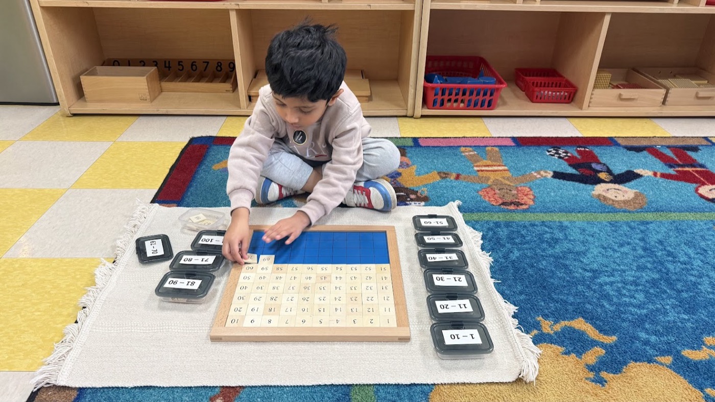 Child placing number tiles on a Montessori math board